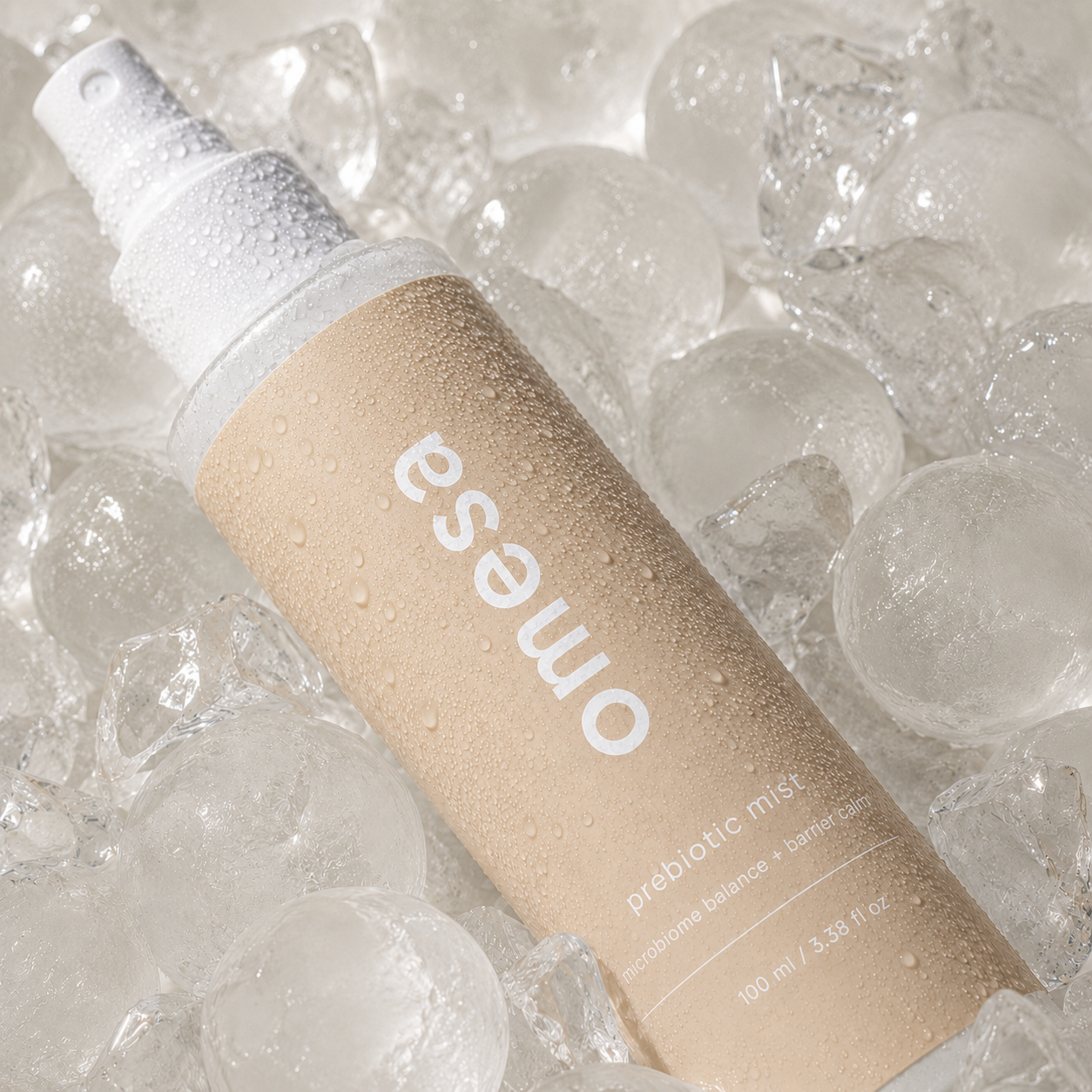 OMESA Prebiotic Mist Gesichtsspray auf Eis mit Wassertropfen, erfrischende Hautpflege für Feuchtigkeit und ein frisches Hautgefühl.